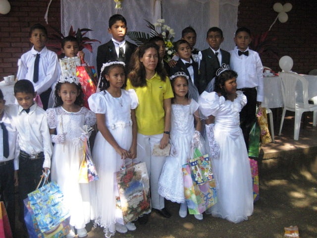 Ninos y Ninas que dieron su Primera Comunion en la Iglesia de Campo de Aterrizaje, acompanados de la profesora Lucila Murillo